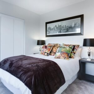 Stylish and contemporary bedroom featuring a cityscape artwork, colorful pillows, and modern decor.